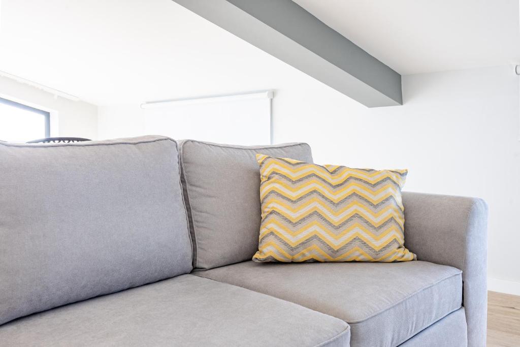ein graues Sofa mit einem gelben Kissen darauf in der Unterkunft Palm Breeze Loft in Estreito da Calheta