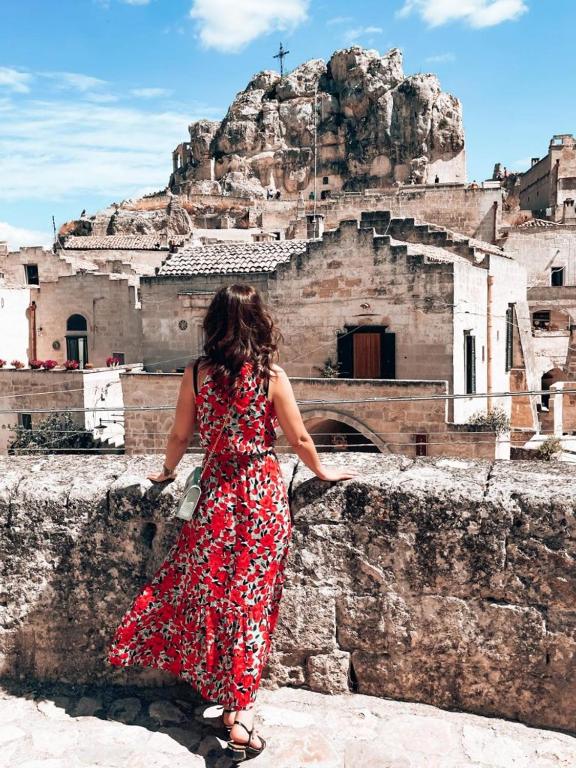 a woman in a red dress standing on a wall at Animæ Caveoso Suite in Matera