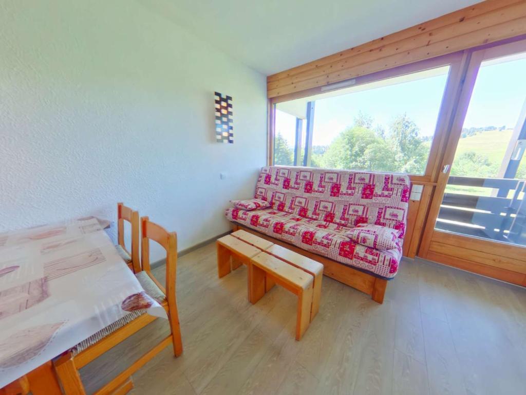 une chambre avec un canapé, une table et une fenêtre dans l'établissement Studio cosy avec alcôve, proche centre des Saisies, balcon sud, 4 pers., classé 2*. - FR-1-594-147, à Hauteluce