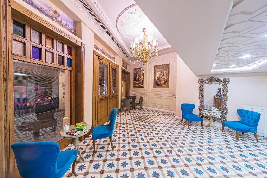 イスタンブールにあるアダカラコイホテル スペシャルカテゴリーの青い椅子、テーブル、シャンデリアが備わる客室です。