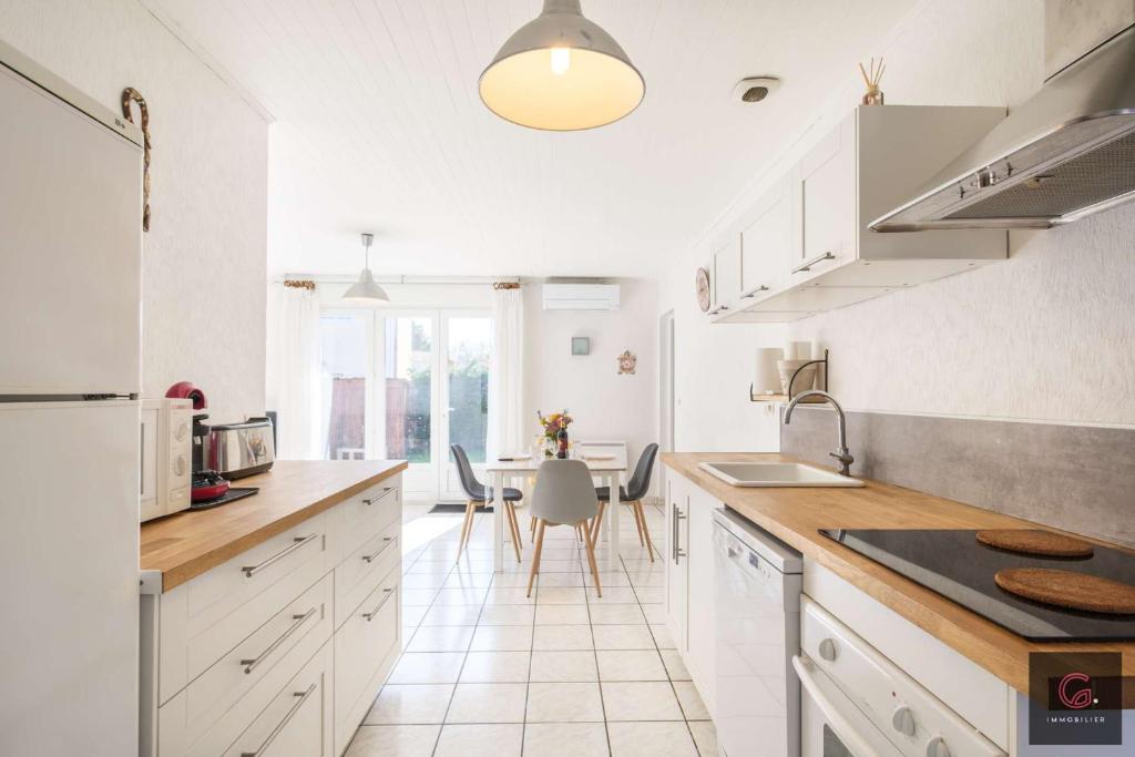 une cuisine avec des armoires blanches et une table avec des chaises dans l'établissement Maison de Vacances à Biscarrosse – Proche du Lac de Latécoère 5 personnes, à Biscarrosse