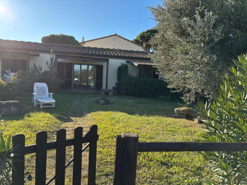 dom z płotem i krzesłem w ogrodzie w obiekcie Casa "Ale" con piscina comune e bellissimo giardino a 5 minuti dal mare w mieście Cecina
