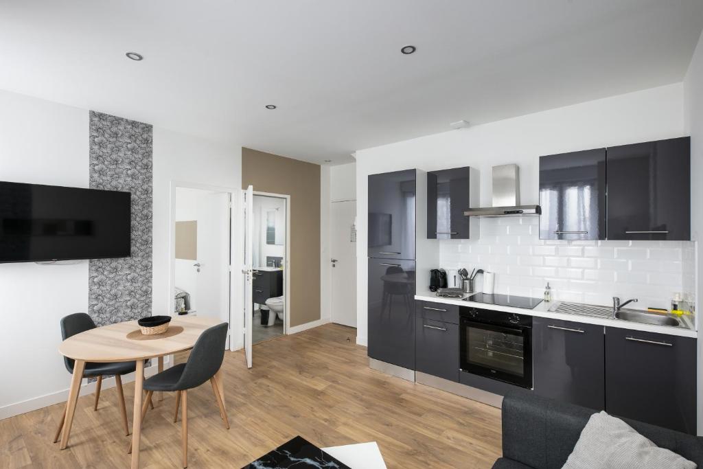 une cuisine avec des armoires noires, une table et des chaises dans l'établissement T2 L'Indomptable, à Brest
