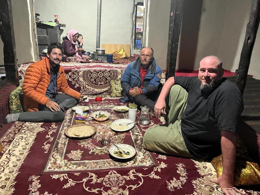 a group of men sitting around a table with food at Pamir Serai in Dargai