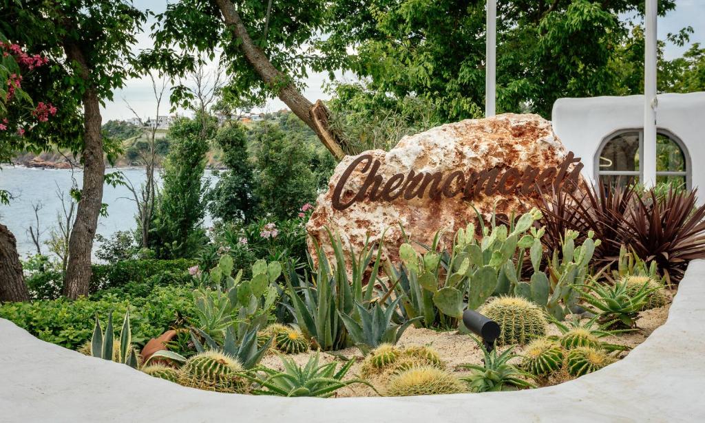 a sign in the middle of a garden with plants at Noma Beach Resort in Chernomorets