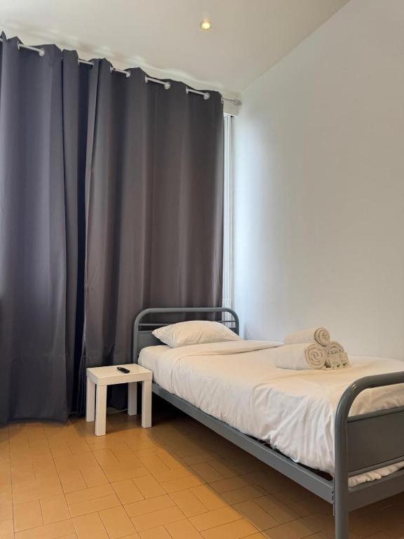 une chambre avec deux lits avec des rideaux gris dans l'établissement Cozy Urban - Close to Paris CDG, à Sarcelles