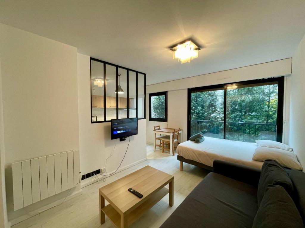 Un dormitorio con una cama, un sofá y un televisor. en Studio Tour Eiffel La Muette, en París
