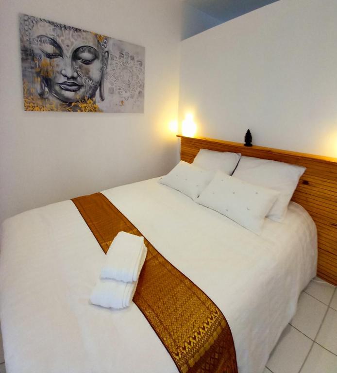 une chambre avec un lit blanc avec un tableau sur le mur dans l'établissement Maison chez nous, à Saint-Priest