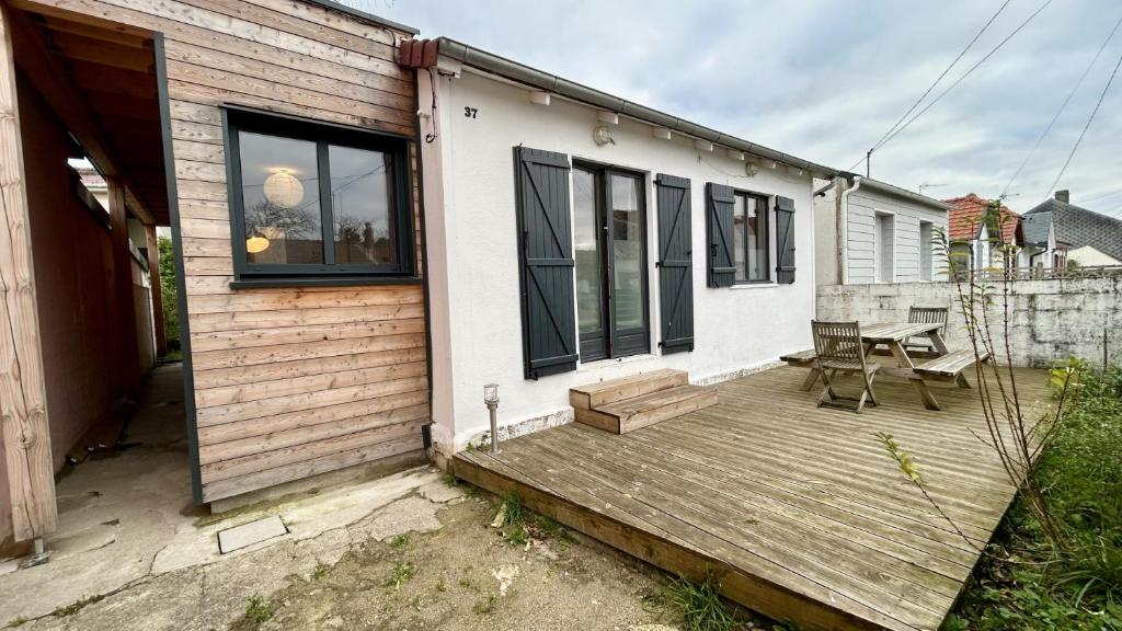 une terrasse en bois à côté d'une maison avec une table dans l'établissement Le Crotoy et moi, au Crotoy