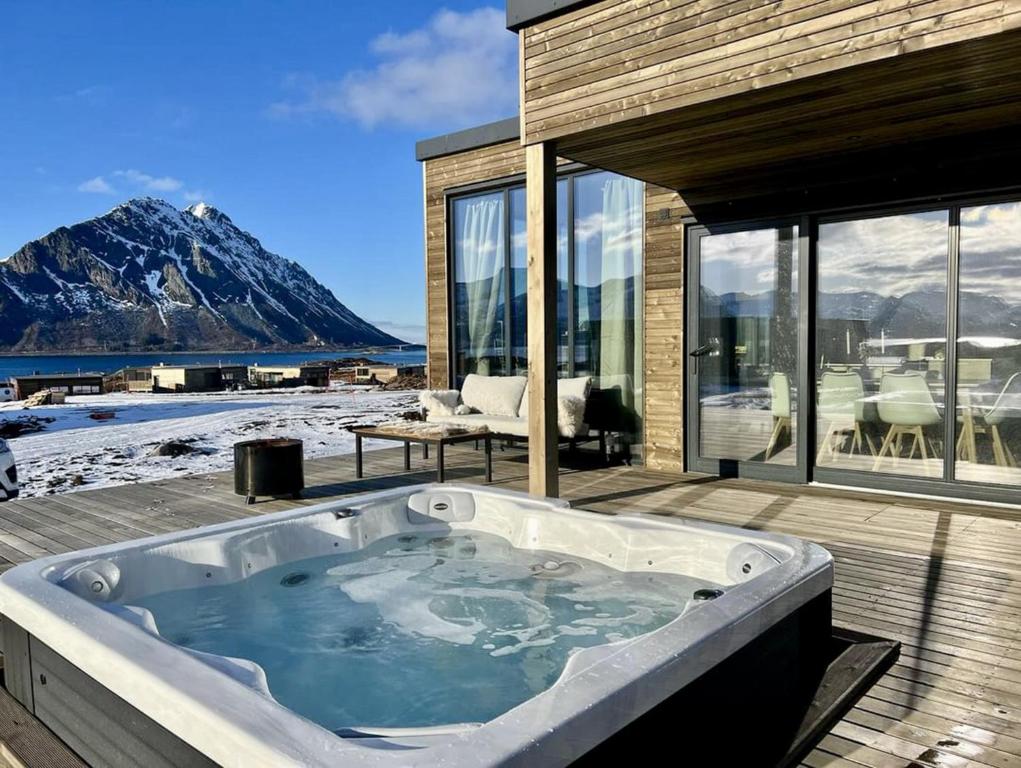 a jacuzzi tub on a deck with a mountain at Lofoten Aurora Lodge in Lyngværet