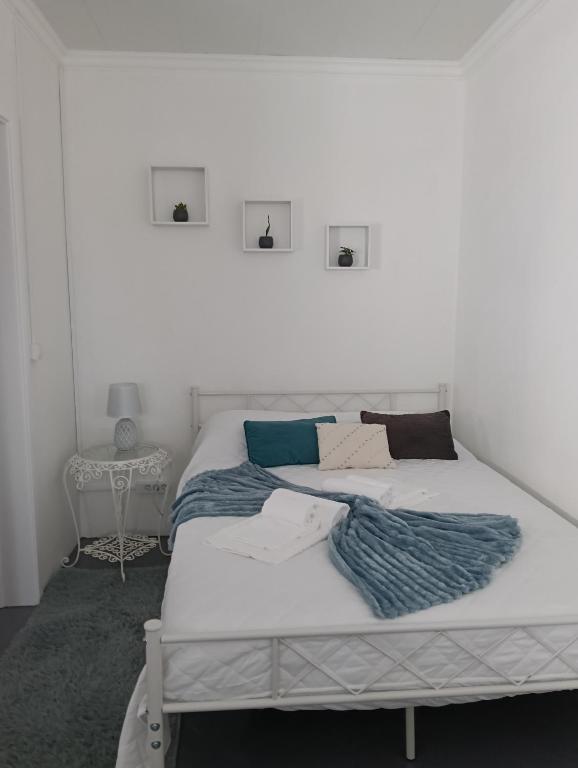 a bedroom with two beds and a white wall at O Aconchegadinho in Rabo de Peixe