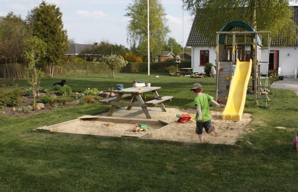 a young boy playing in a park with a playground at Skjoldbjerg Garnihotel in Vorbasse