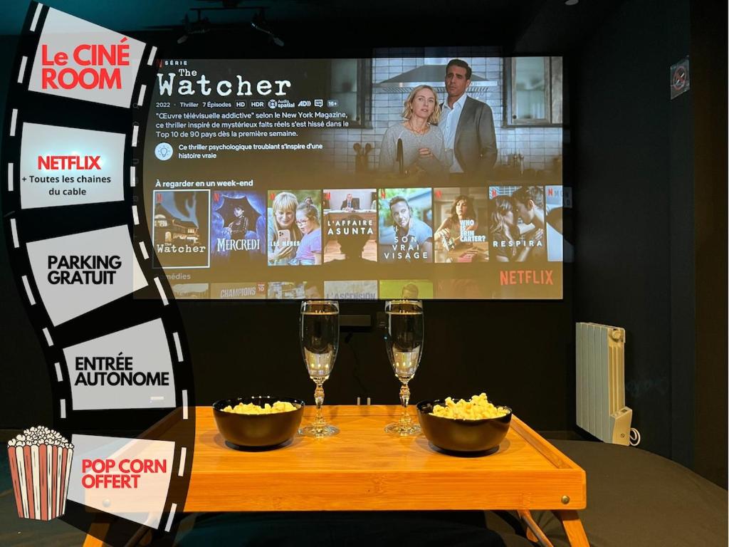 - une table avec deux verres de vin et une télévision dans l'établissement CinéRoom Private Cinema in Bourges, à Bourges