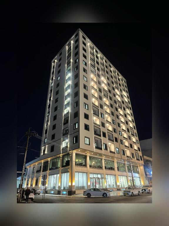 Un edificio alto con coches aparcados delante. en MyFlower 3 Hotel, en Erbil