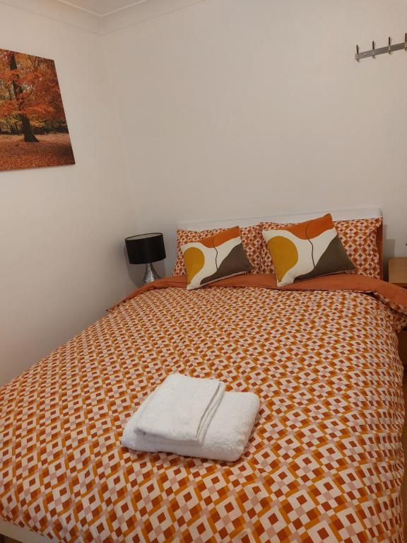 a bed with a white towel on top of it at The Galaxy in Wokingham