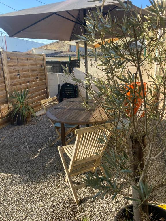 une table en bois avec un parasol et une chaise en bois dans l'établissement maison cosy, à Cambrai