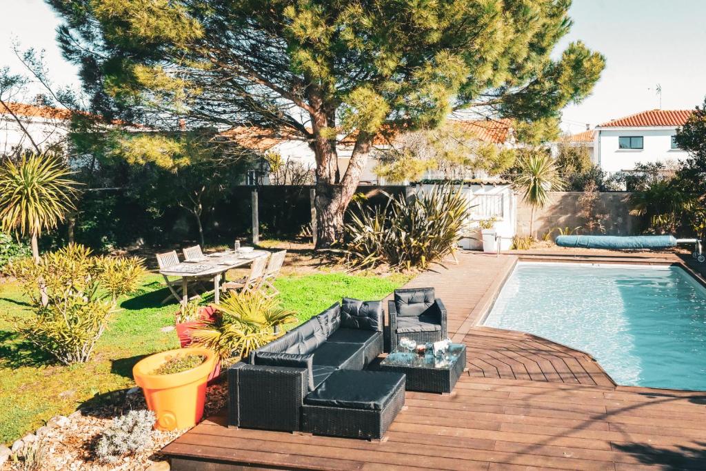une cour arrière avec une piscine et une terrasse avec des plantes dans l'établissement Belle maison de vacances avec piscine - 8 personnes, à Les Sables-dʼOlonne