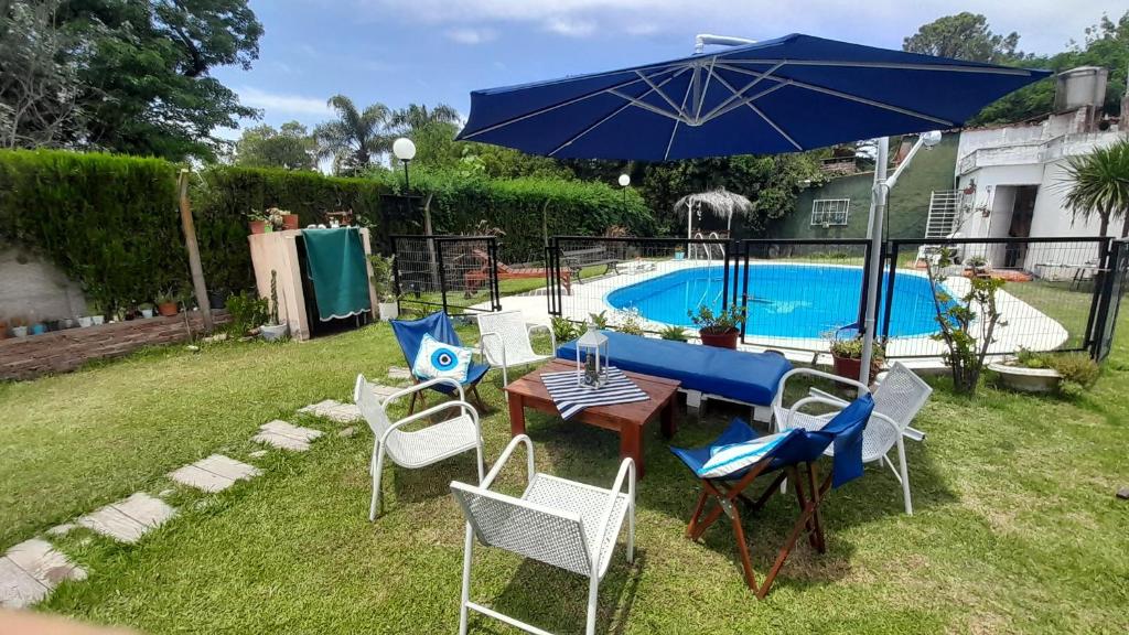 einen Tisch und Stühle mit einem Sonnenschirm neben einem Pool in der Unterkunft CASA DE CAMPO cerca de rosario in Pueblo Esther