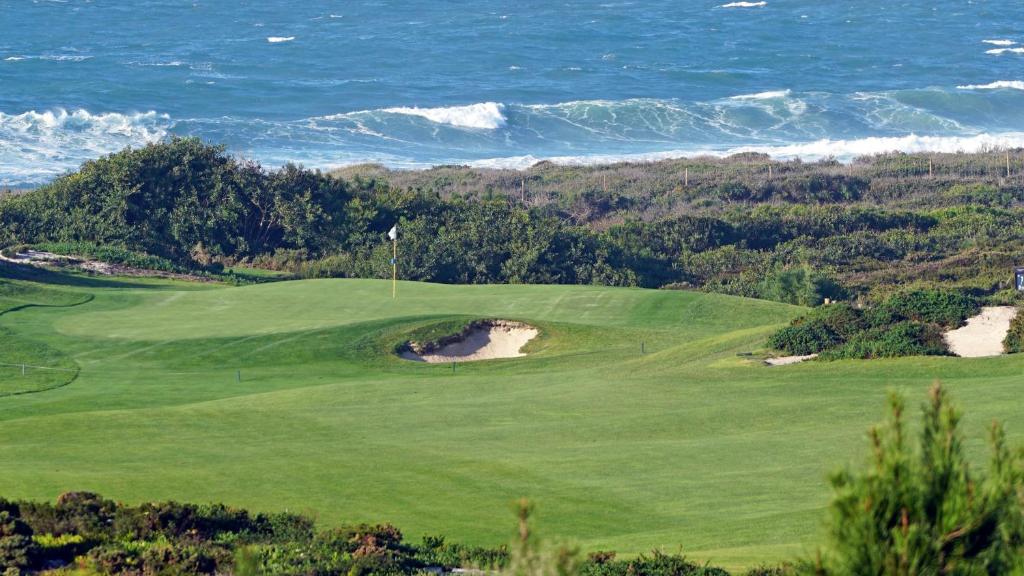 un campo da golf verde con l'oceano sullo sfondo di Silver Coast Sunset View ad Atouguia da Baleia