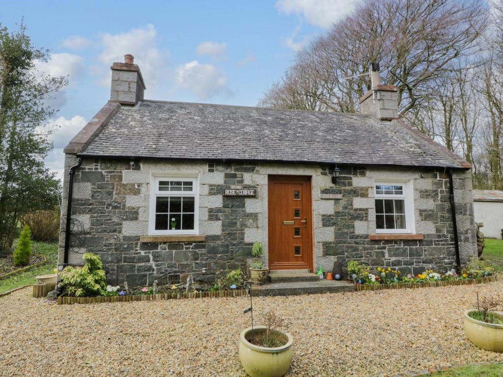 a small stone house with a red door at Rose Cottage in Stranraer