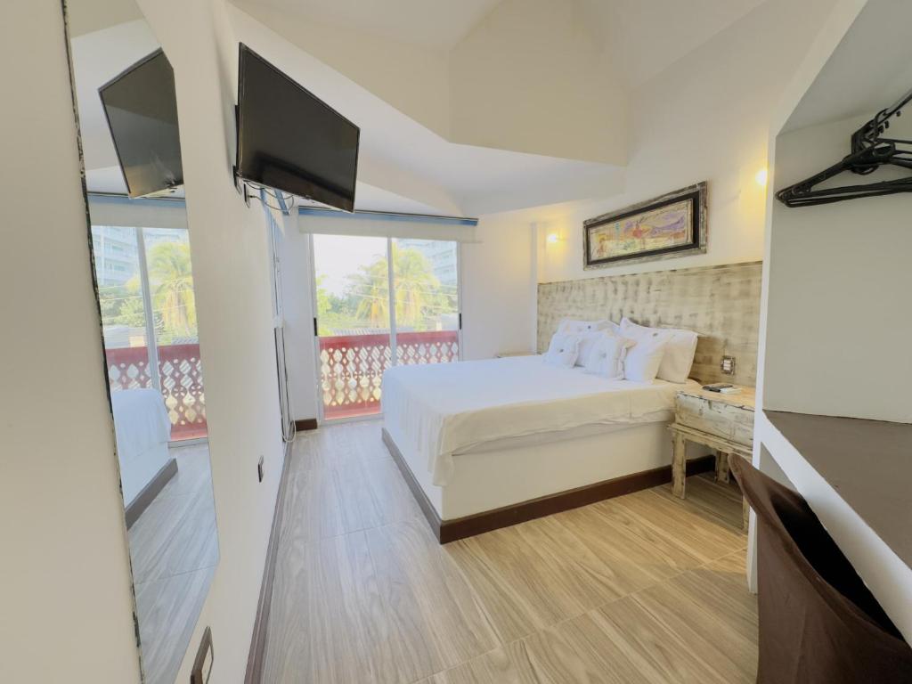 a bedroom with a white bed and a television at Auaecoco Hotel in Cartagena de Indias