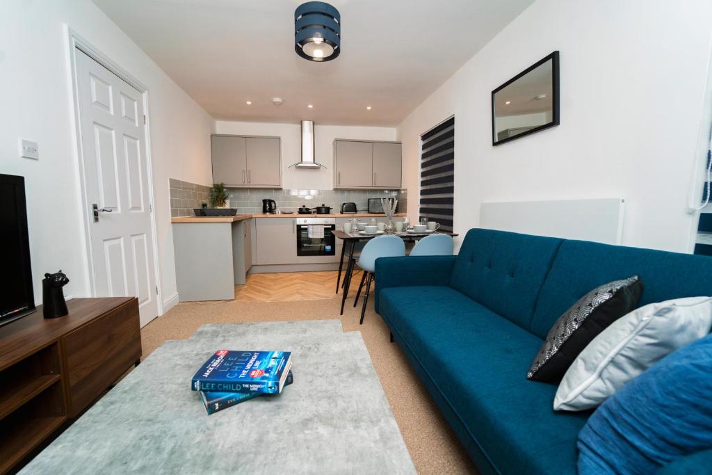 a living room with a blue couch and a kitchen at Stunning New Town Centre flat in Wigan in Wigan