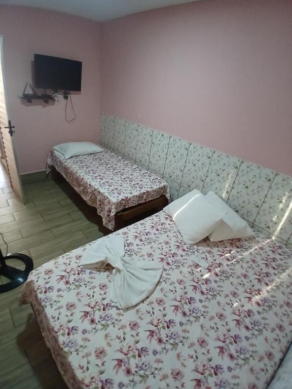 two beds sitting in a room with a tv at kitnet pé na areia reservado por sayonara in Ilhéus