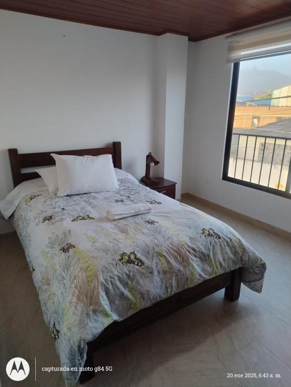 a bedroom with a bed with a floral bedspread and a window at Apartamento el Rubí 202 in Cómbita