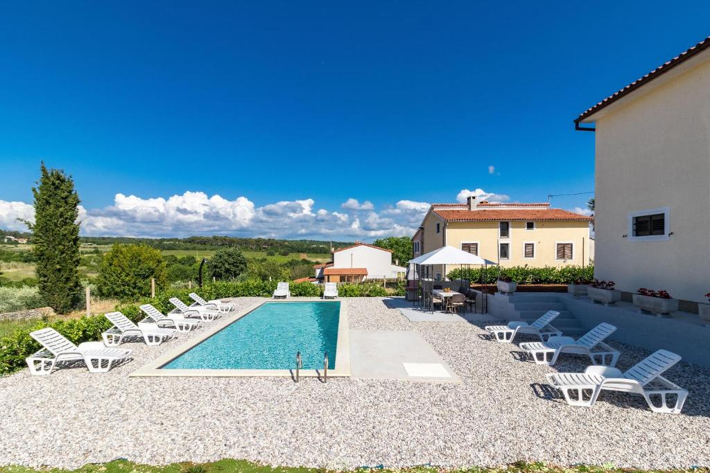 a swimming pool with lounge chairs and a house at House Lilly in Višnjan