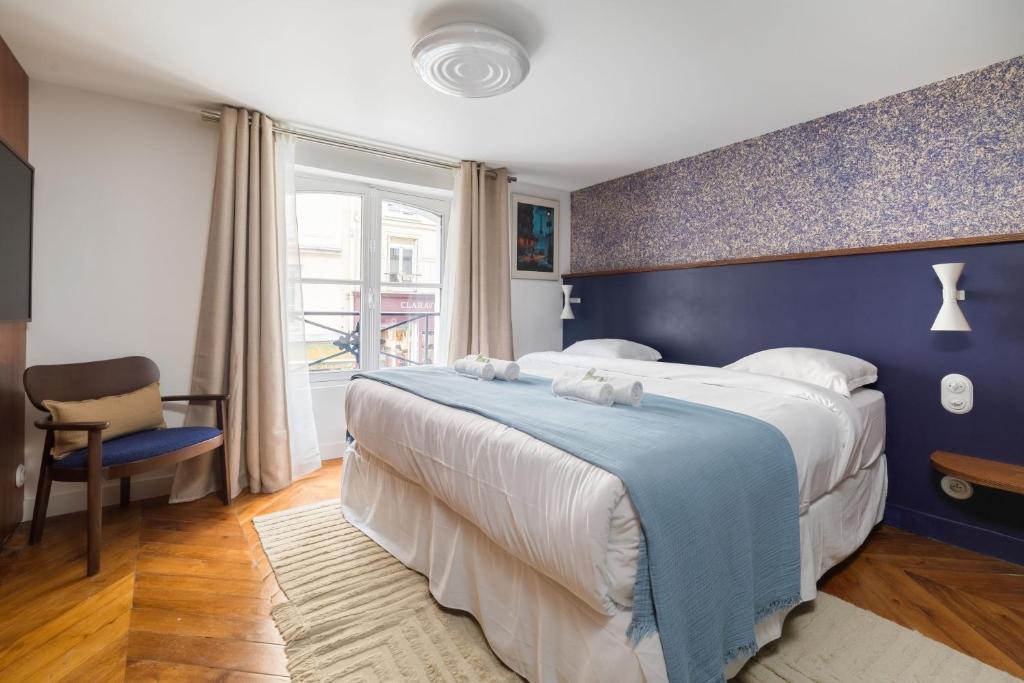 une chambre avec un grand lit avec un mur bleu dans l'établissement Paris La Belle - Marais, à Paris
