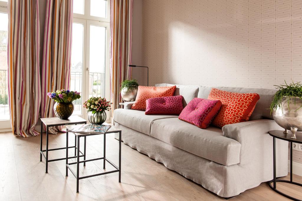 a living room with a couch with colorful pillows on it at Hotel Sylter Zollhaus in Westerland