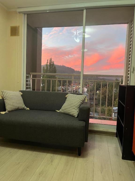 a living room with a couch in front of a large window at Departamento acogedor y céntrico in Temuco