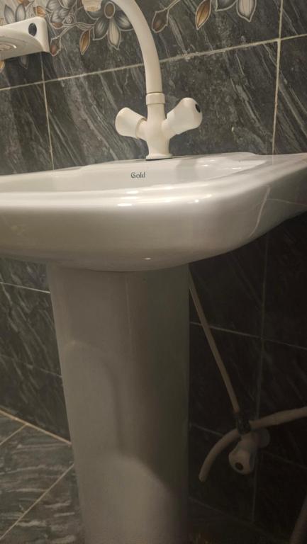 Un lavabo blanco con grifo en un baño. en Hotel White Pearl, en Karachi