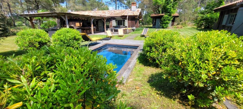 une cour arrière avec une piscine et une maison dans l'établissement 4 Cabanes de luxe privatisées à 300m de la Dune, à La Teste-de-Buch