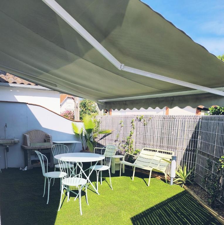 d'une terrasse avec une table et des chaises sous un auvent. dans l'établissement Maison souvenir, à Andernos-les-Bains