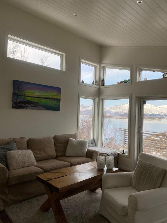 a living room with a couch and a table and windows at Practical and cozy cottage in idyllic Senja 3 bedrooms in Senja