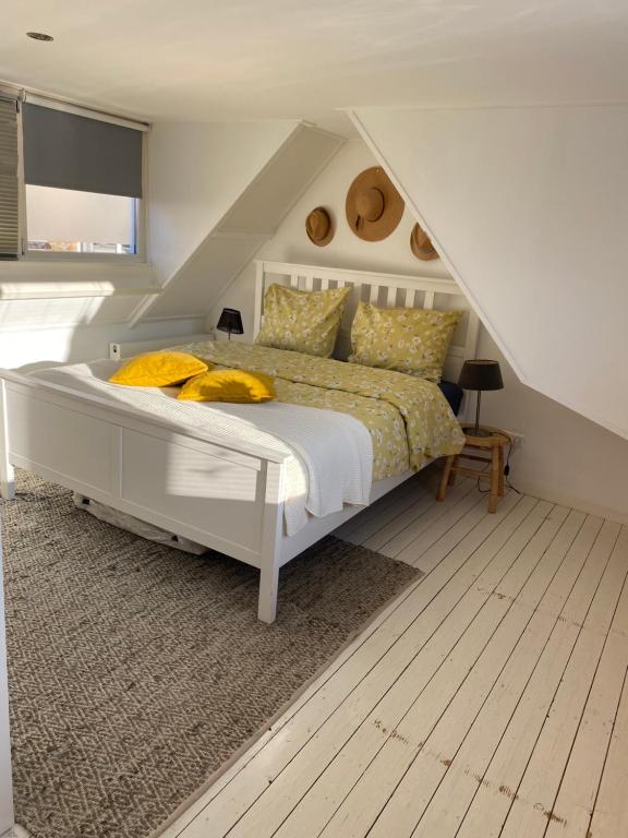 a bedroom with a white bed with yellow pillows at Appartement 4 Seasons Katwijk aan Zee in Katwijk aan Zee