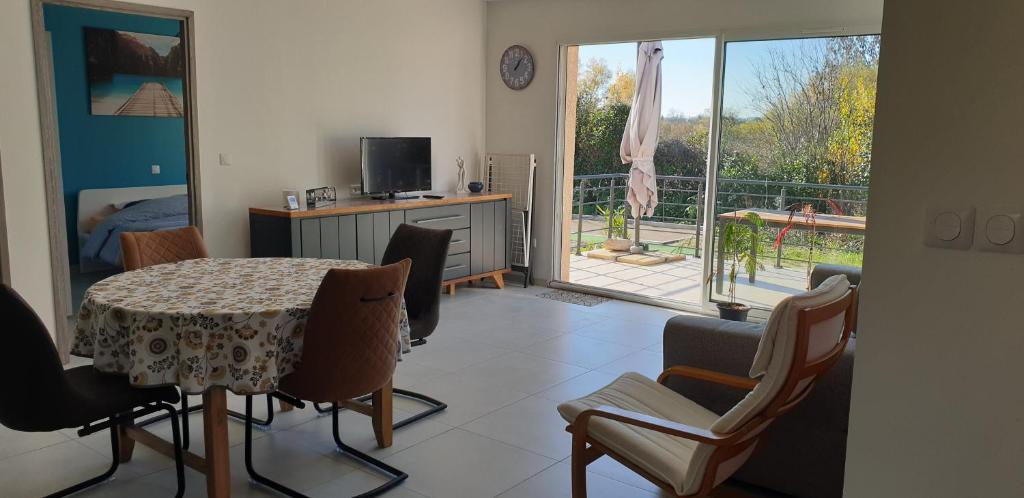 un salon avec une table et des chaises et un balcon dans l'établissement Maison de vacances, à Pézenas