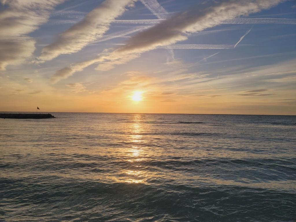 un coucher de soleil sur l'océan avec le soleil dans le ciel dans l'établissement Lidou, à Menton