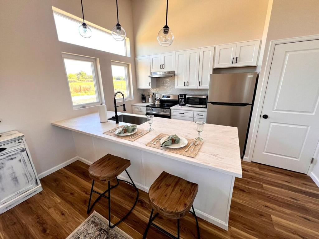 a kitchen with a large island with two stools at Posh Cottage Wine Country Mountain View Retreat in Palisade