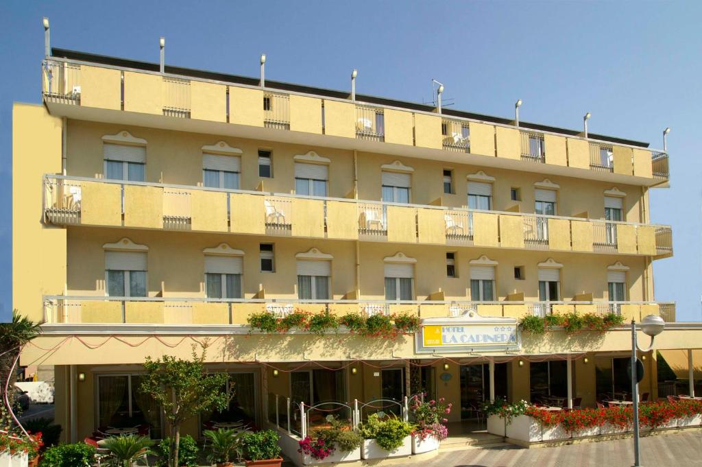 ein großes gelbes Gebäude mit Blumentopfen davor in der Unterkunft Hotel La Capinera in Bellaria-Igea Marina