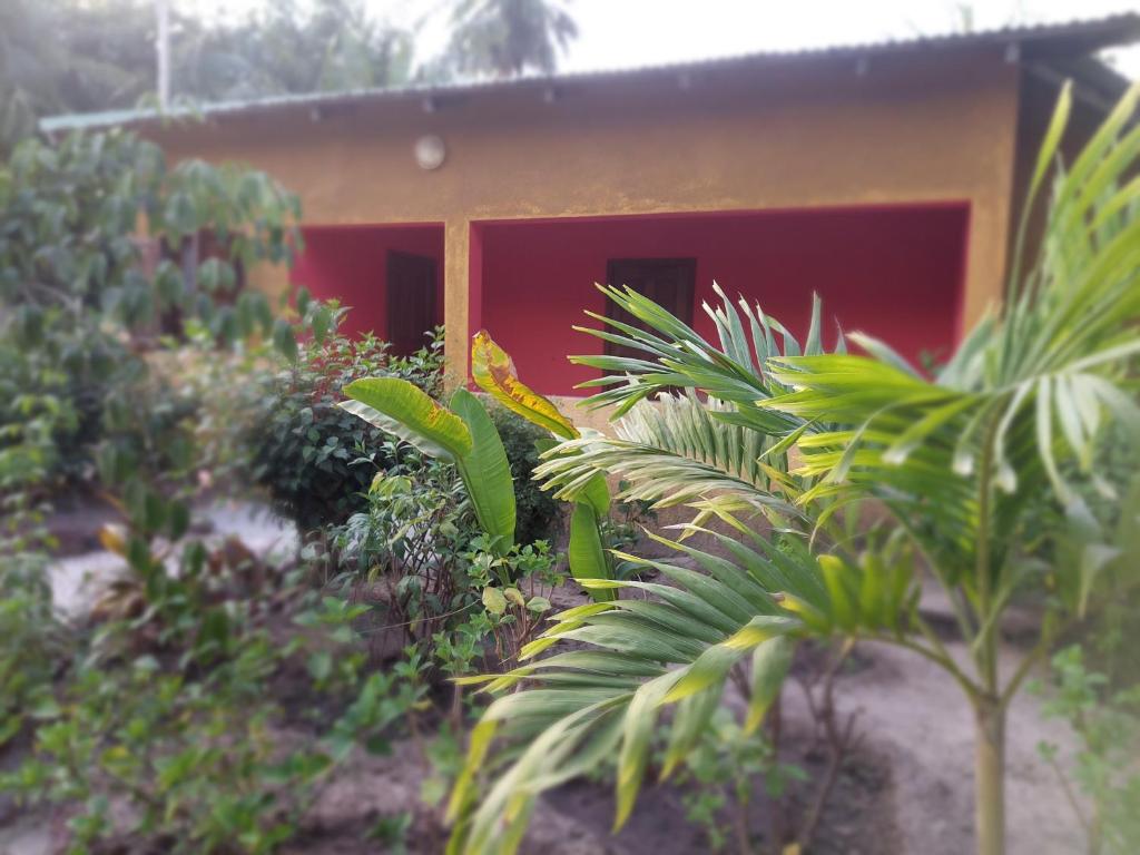 a small house with a red door in a garden at Bolongs Passion in Cap Skirring