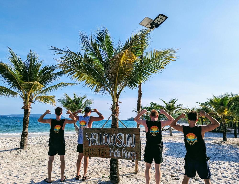 Un grupo de hombres de pie alrededor de un cartel en la playa. en Yellow Sun Koh Rong, en Kaôh Rŭng (3)
