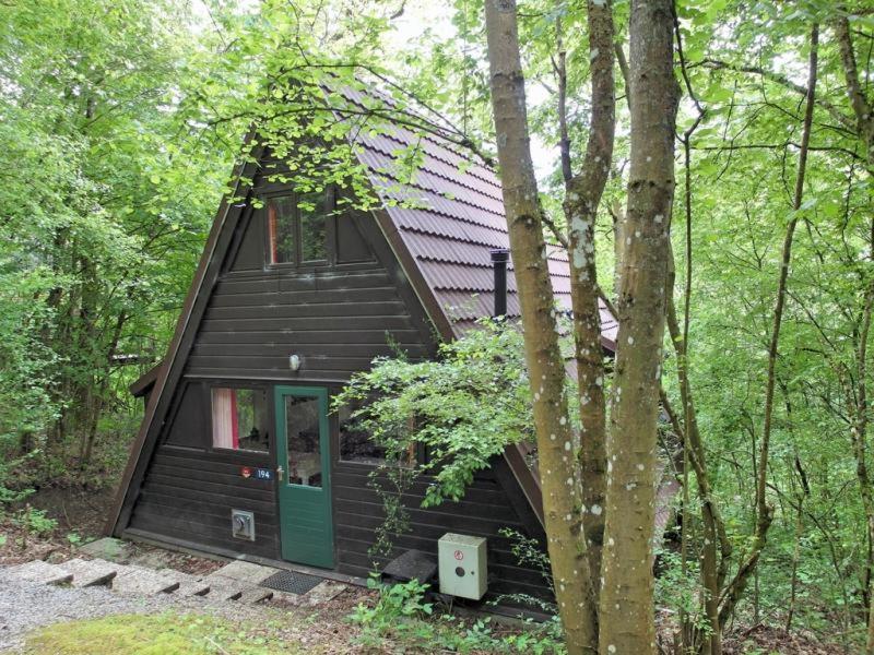 eine Hütte im Wald mit grüner Tür in der Unterkunft Durbuy Bungalow 194, calme et nature in Durbuy