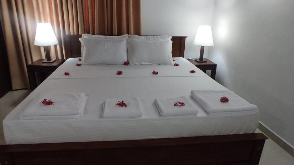 Una cama con sábanas blancas y flores rojas. en Royal home stay 2 bedroom private home in secure private property with garden view and all the facilities, en Kalutara South