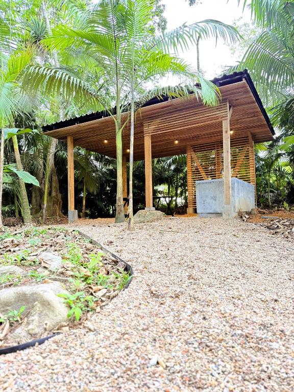 a wooden pavilion with palm trees in front of it at Camping do Bosque - Deck 01 in Rodeio