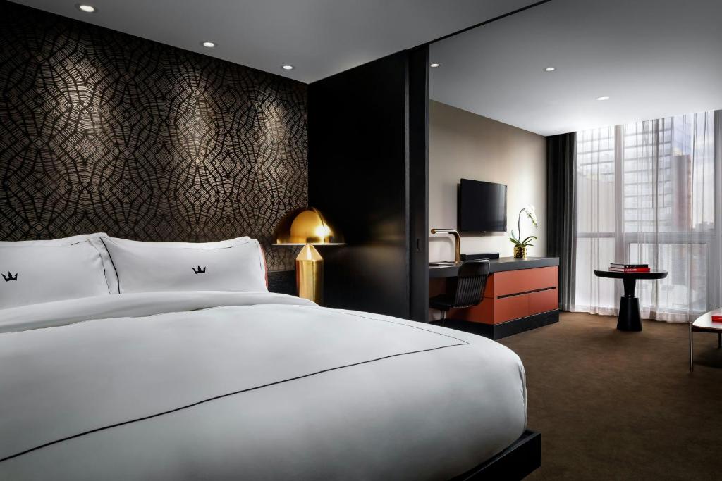 a bedroom with a large white bed and a television at BISHA, a Luxury Collection Hotel, Toronto in Toronto