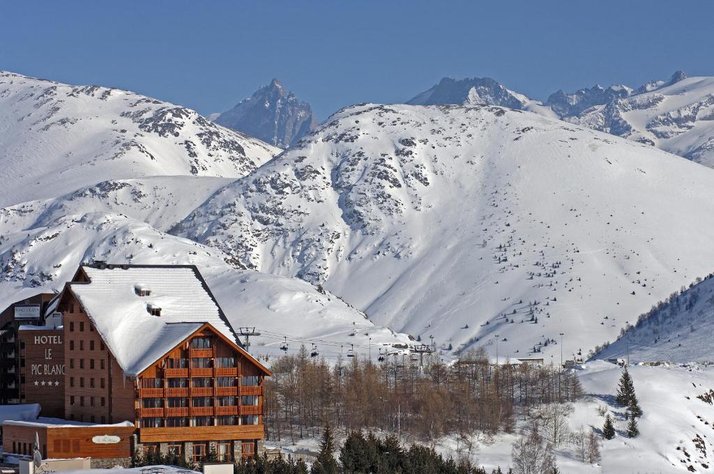 a ski lodge with snow covered mountains in the background at Le Pic Blanc in L'Alpe-d'Huez