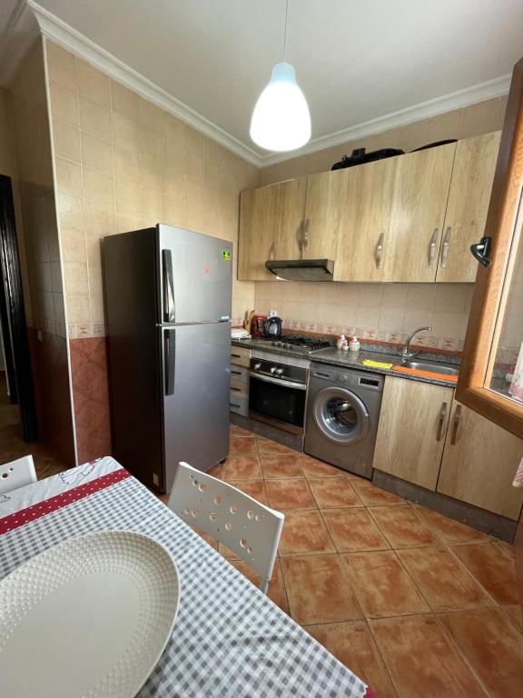 una cucina con frigorifero in acciaio inox e tavolo di Résidence avec piscine près de la plage Martil a Martil