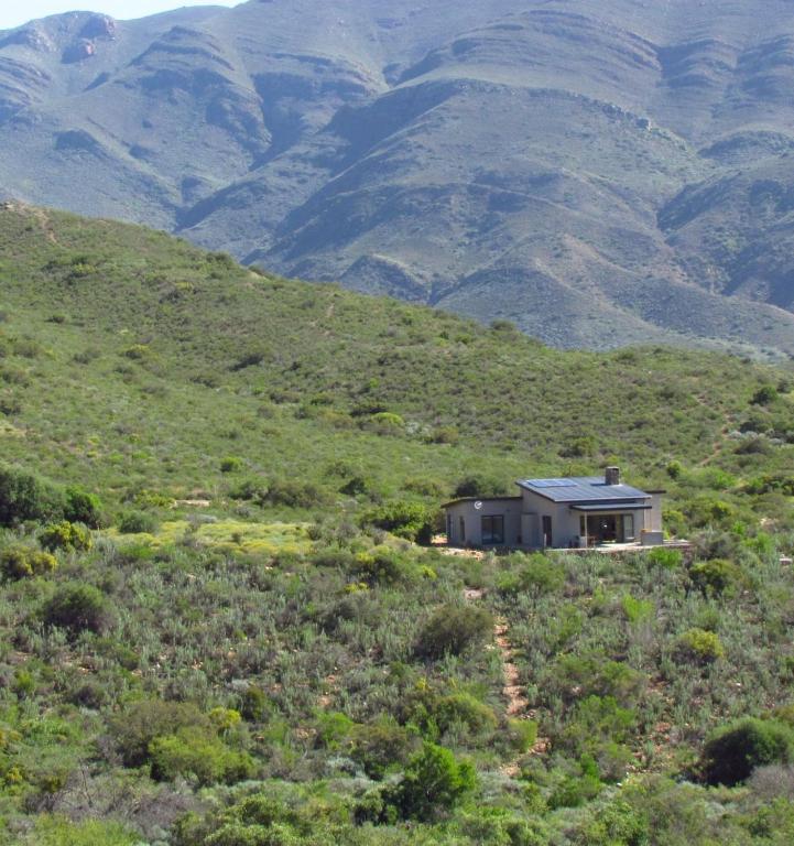 a house on a hill with mountains in the background at Exhale Cottage in Montagu